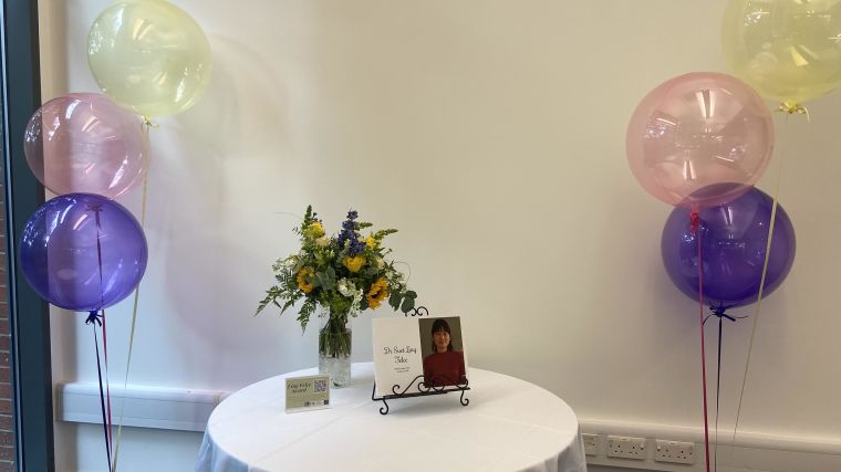 Table with flowers and a memory book on, with balloons either side